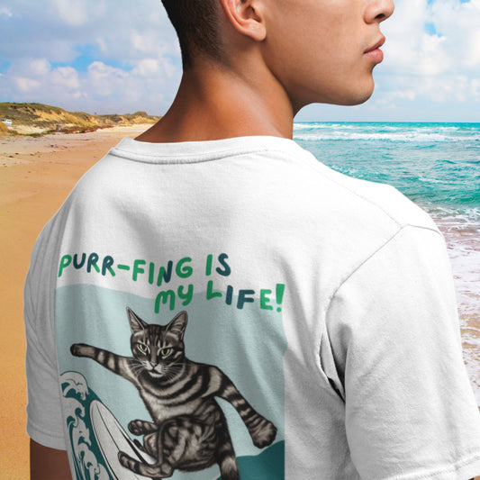 Close up of a young man sports a stylish white cotton short-sleeve t-shirt adorned with a whimsical design of a surfing cat and the amusing phrase 'Purr-fing is my life!' on the back, capturing his joy and humor.