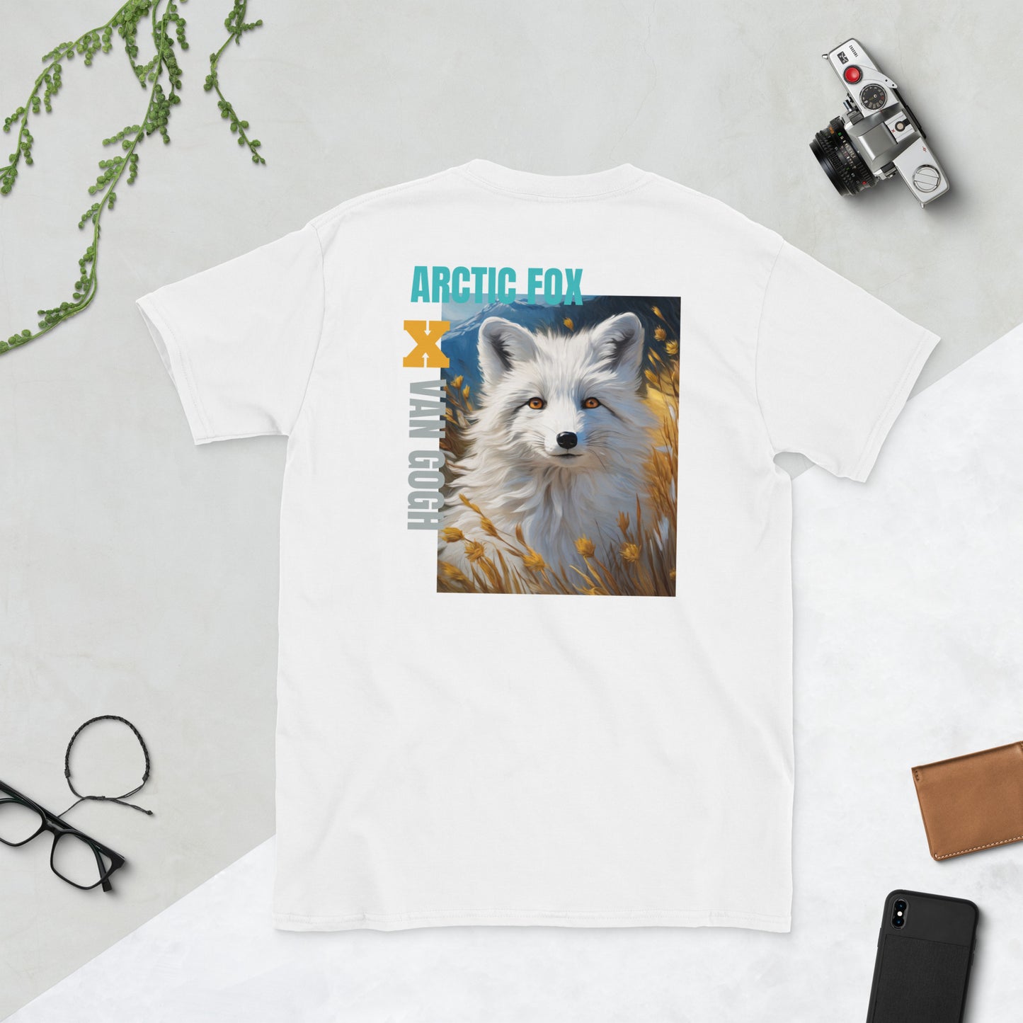 Back graphic of a White Fox in Wheat T-Shirt in white, featuring an artistic white fox design surrounded by a wheat field, inspired by Van Gogh’s Wheat Field. Lay flat styling with lifestyle items like a camera and phone beside it, showcasing a creative and modern vibe.