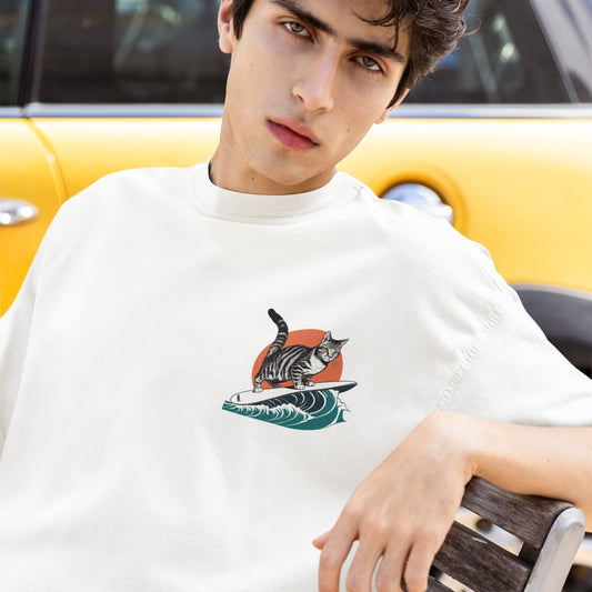 Close-up of a young man wearing a white minimalist graphic t-shirt, featuring a small surfing cat design on the front left chest. A cool and subtle cat shirt for men.