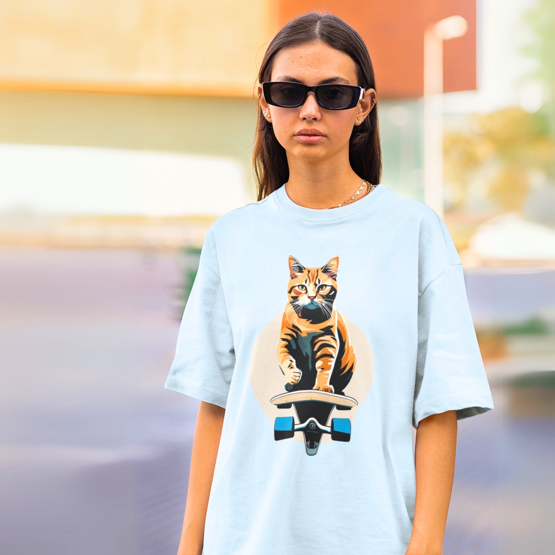 Young woman wearing a light blue cool t-shirt featuring a playful skateboarding cat design. A stylish and fun shirt for cat lovers!