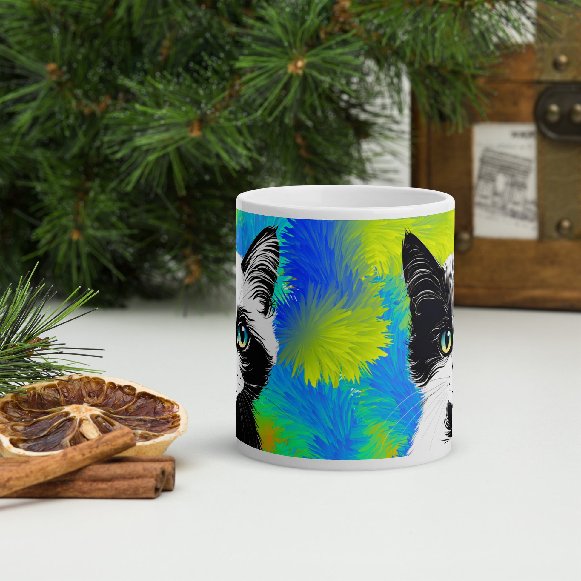 A front view of a white glossy ceramic mug with an artistic cat design, elegantly placed on a tastefully decorated table.