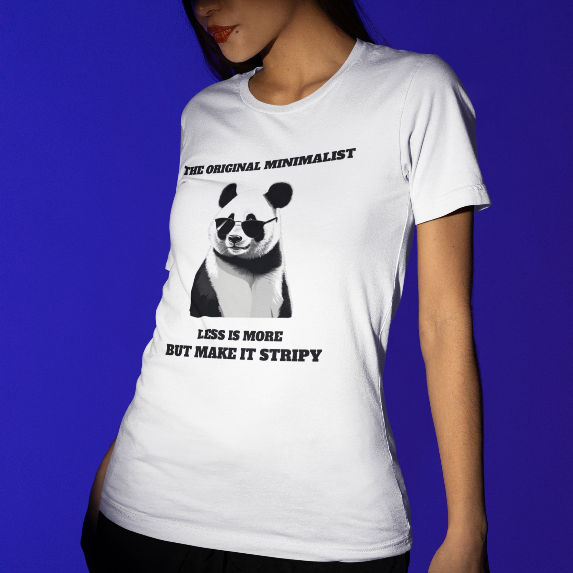 Woman wearing white minimalist panda graphic tee with sunglasses and quote: 'THE ORIGINAL MINIMALIST, LESS IS MORE, BUT MAKE IT STRIPY.' Soft cotton unisex humor t-shirt.