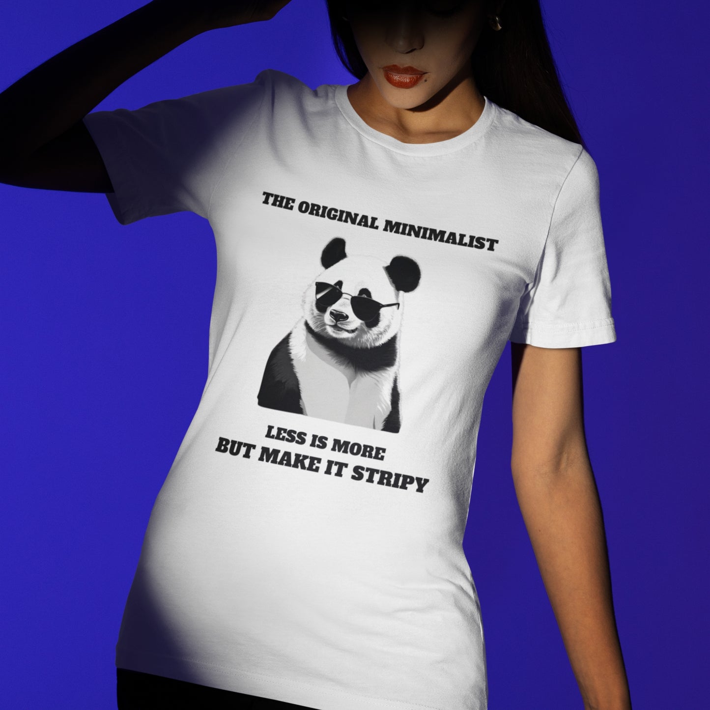 Woman wearing white minimalist panda graphic tee with sunglasses and quote: 'THE ORIGINAL MINIMALIST, LESS IS MORE, BUT MAKE IT STRIPY.' Soft cotton unisex humor t-shirt.