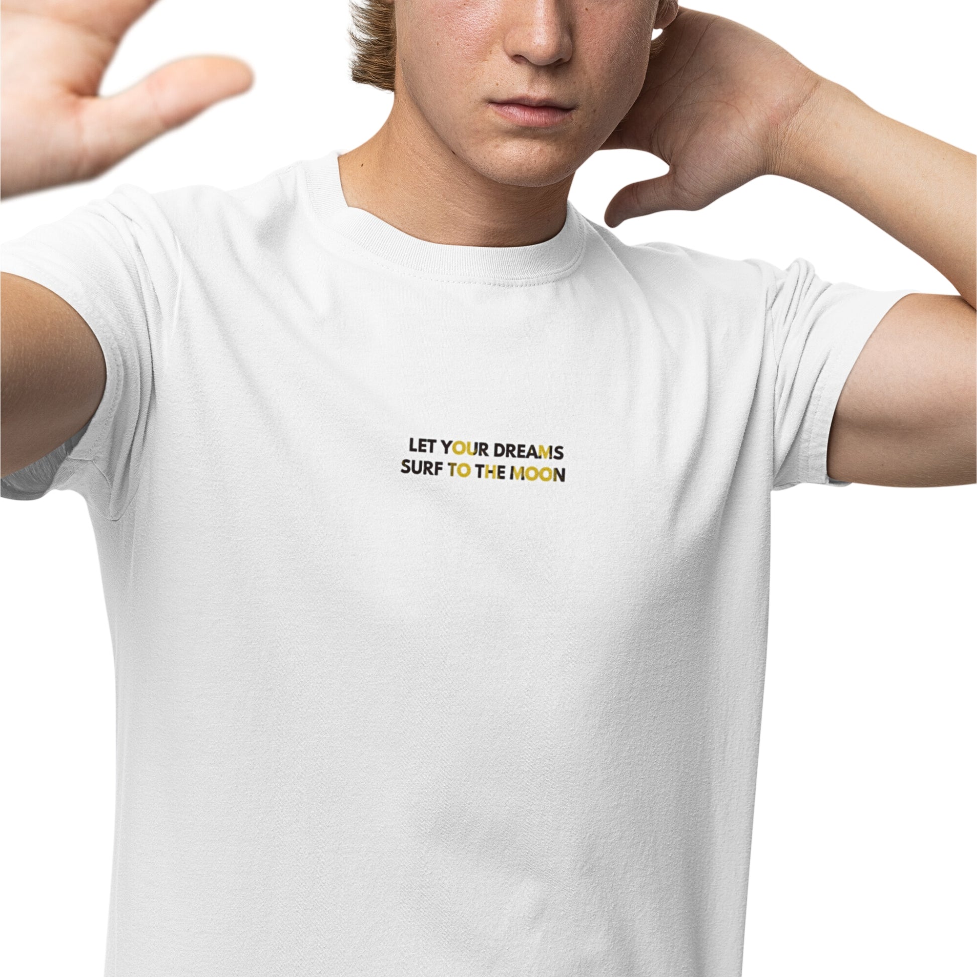 A young man wearing a white cotton T-shirt with a 'Let Your Dreams Surf to the Moon' graphic, posing for the camera.