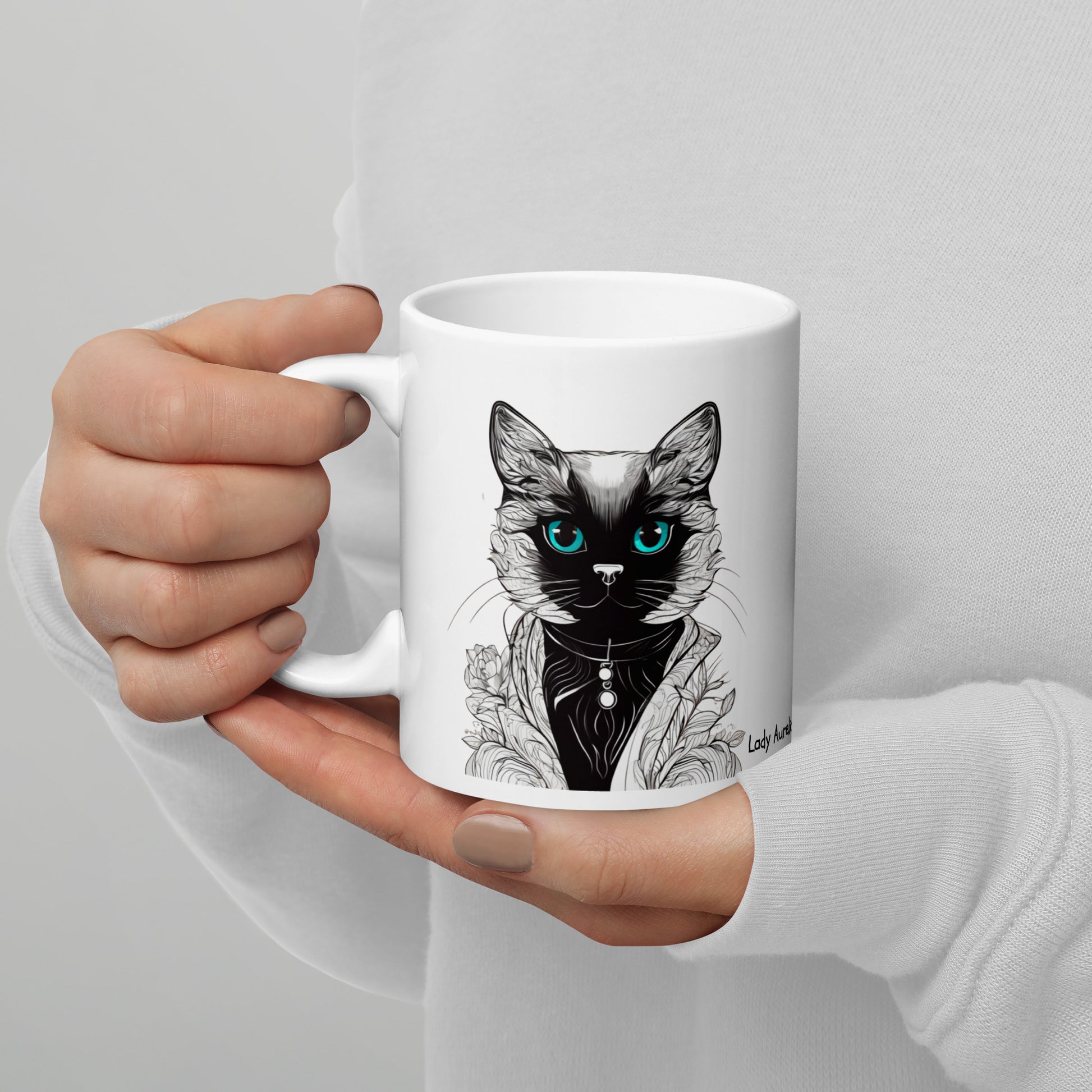 Close-up of a woman's hand holding a royal cat coffee mug adorned with a royal cat lady design.