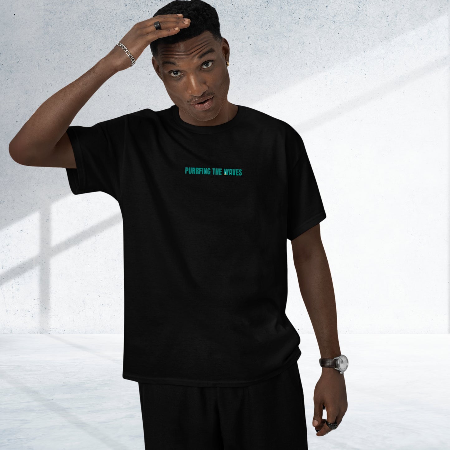 A young man wearing a black funny cat tee shirt, featuring the playful text: 'Purrrfing the Waves' printed on it. A cool and humorous design for cat lovers!