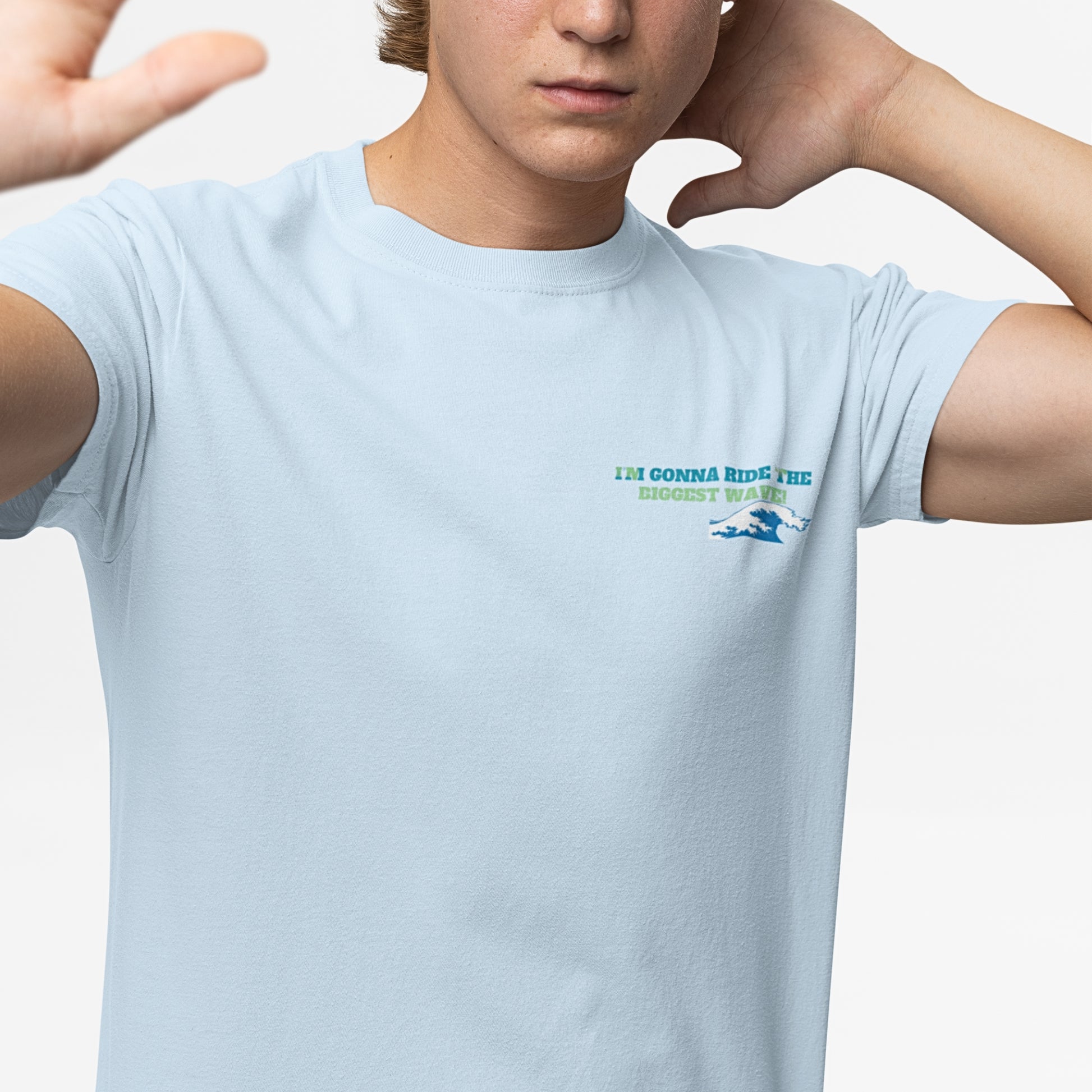A young man wearing a light blue cotton t-shirt featuring playful front text: 'I'm gonna ride the biggest wave.' A cool and humorous cat funny t-shirt design for cat lovers.