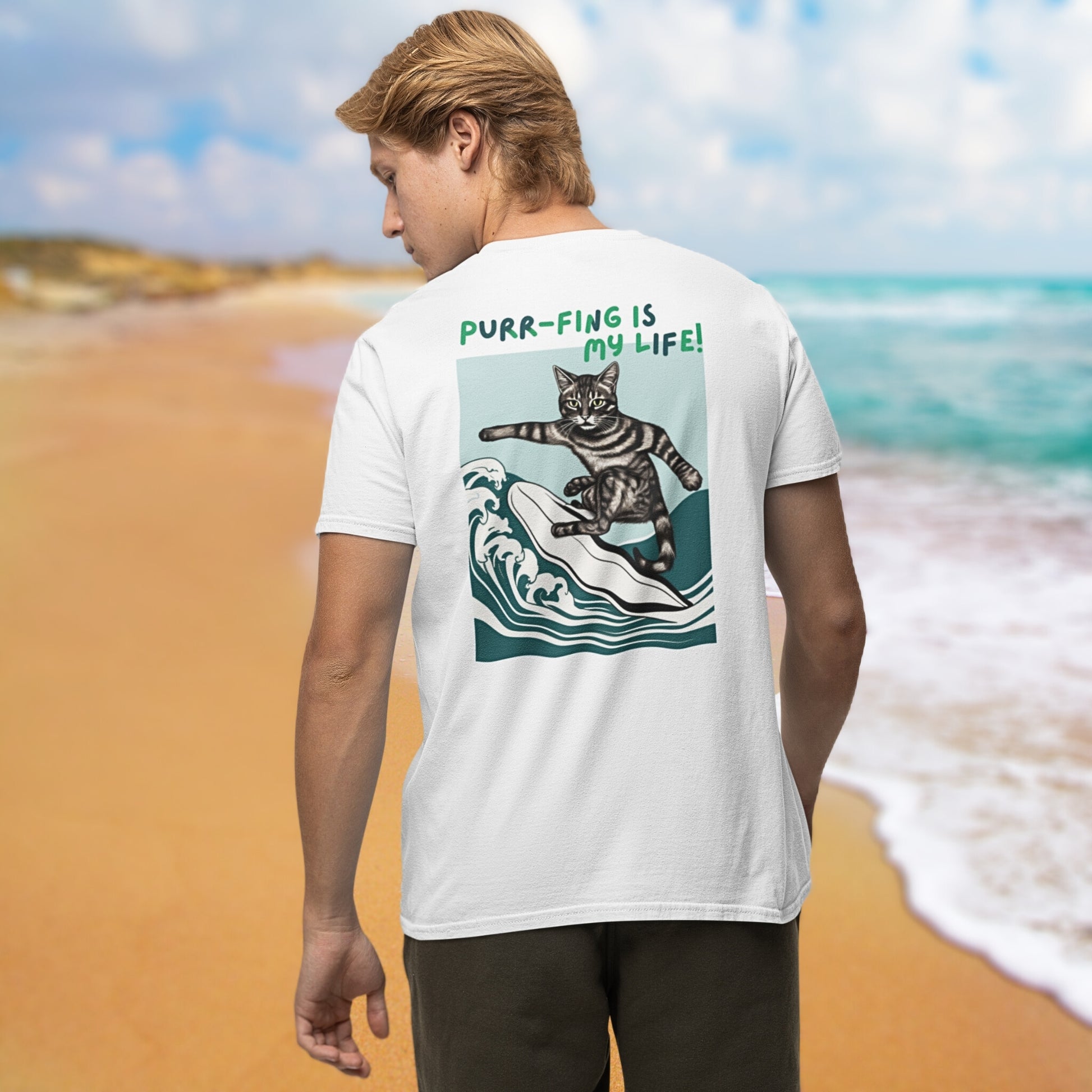 From the back view, a young man sports a stylish white cotton short-sleeve t-shirt adorned with a whimsical design of a surfing cat and the amusing phrase 'Purr-fing is my life!' on the back, capturing his joy and humor.